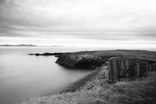 Dramatic basalt column formations curving along Iceland coastline, long exposure silky water, minimalistic, black and white fine art photography by Tamara Gooch