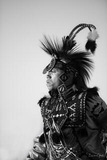 Native American powwow dancer in feathered roach headdress and ceremonial regalia, black and white fine art portrait by Tamara Gooch.