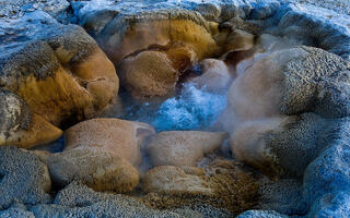 Color fine art close detail of Shell Spring geyser, turquoise boiling water surrounded by textured sinter formations, steam rising, Yellowstone National Park.