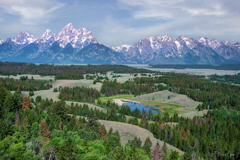 Color fine art photo of the full Teton Range above the forested Jackson Hole valley from a private elevated vantage, small oxbow pond below, Wyoming.