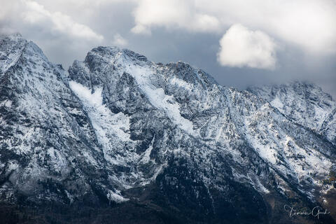 Compressed telephoto view of snow-covered Grand Teton peaks, jagged rock faces and couloirs, dramatic cloud backdrop, Wyoming landscape fine art photograph