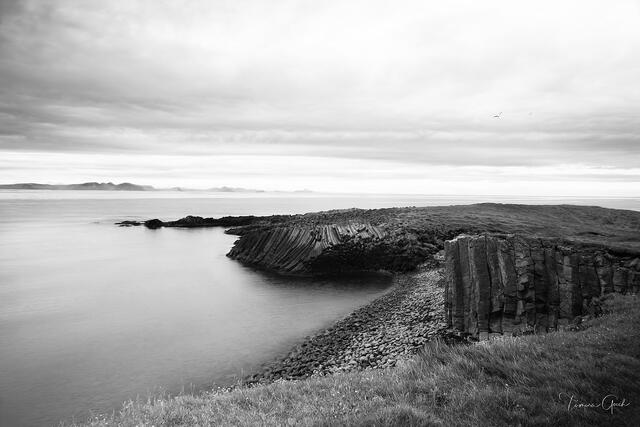 Dramatic basalt column formations curving along Iceland coastline, long exposure silky water, minimalistic, black and white fine art photography by Tamara Gooch