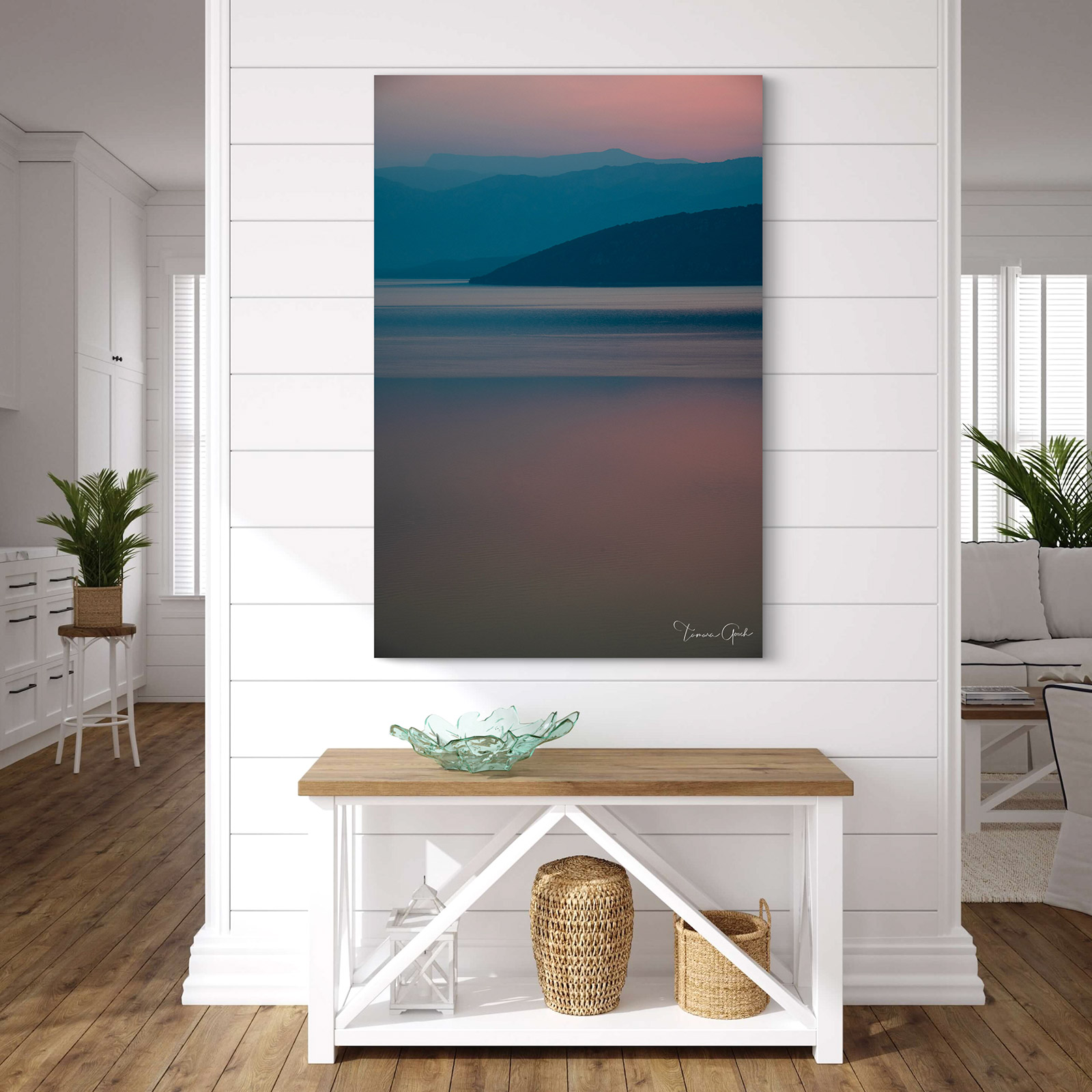 A minimalist fine art photograph of blue mountain silhouettes reflecting in pink twilight water.