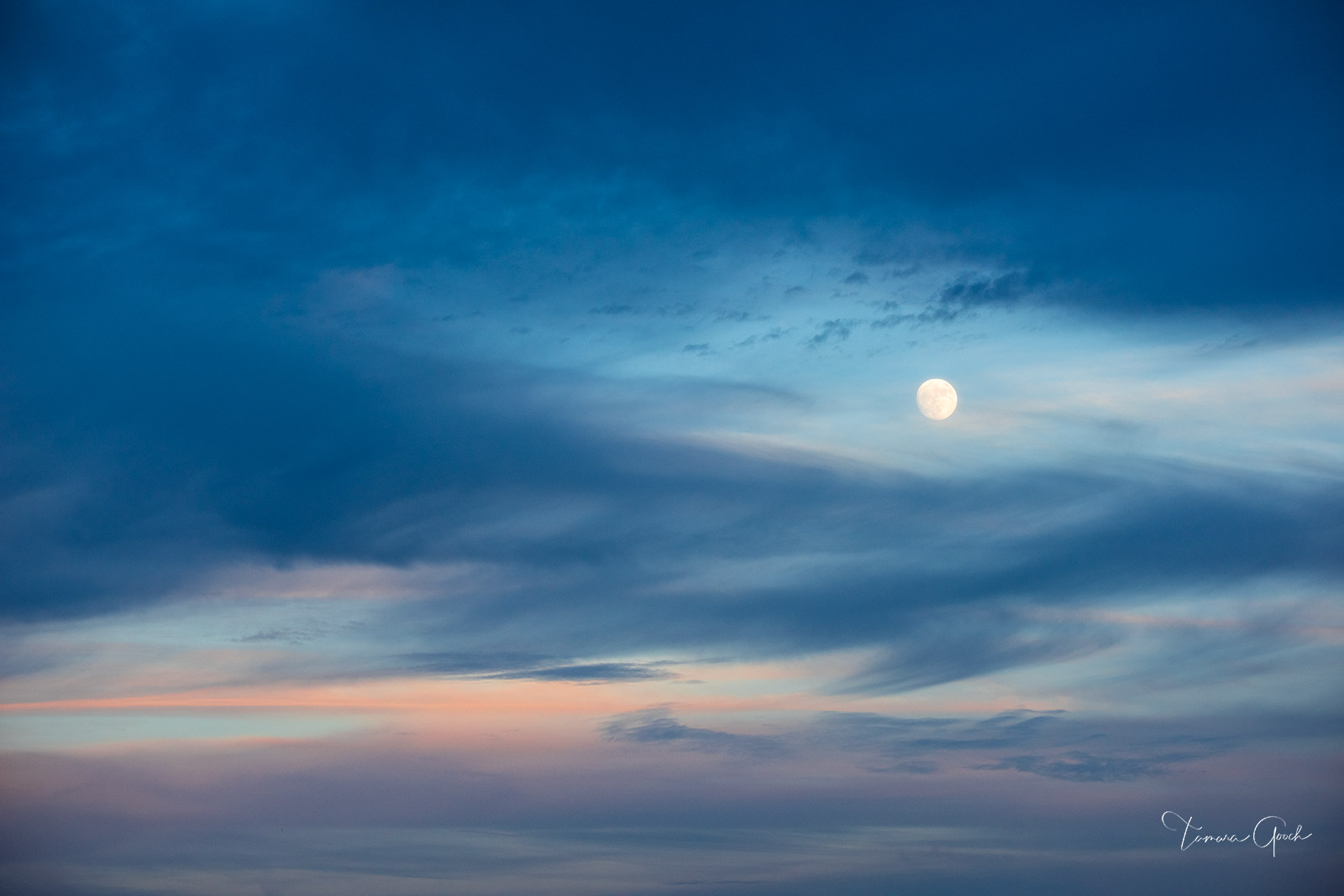 Moonrise The full moon rising between the sunset colored clouds.